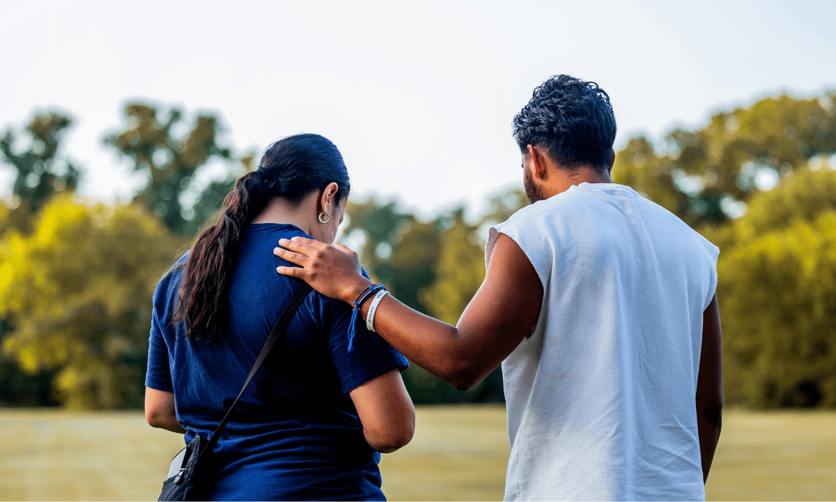 Zia-Recovery-Center-Help-With-Alcohol-Addiction-Empathy1 Support group therapy session with diverse adults standing in a circle, one person offering comfort with a hand on another’s shoulder, symbolizing connection and healing.